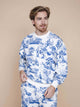 Man in SNURK Toile De Modern Joy Sweater Unisex met blauw-witte print, posed tegen een doffe achtergrond.