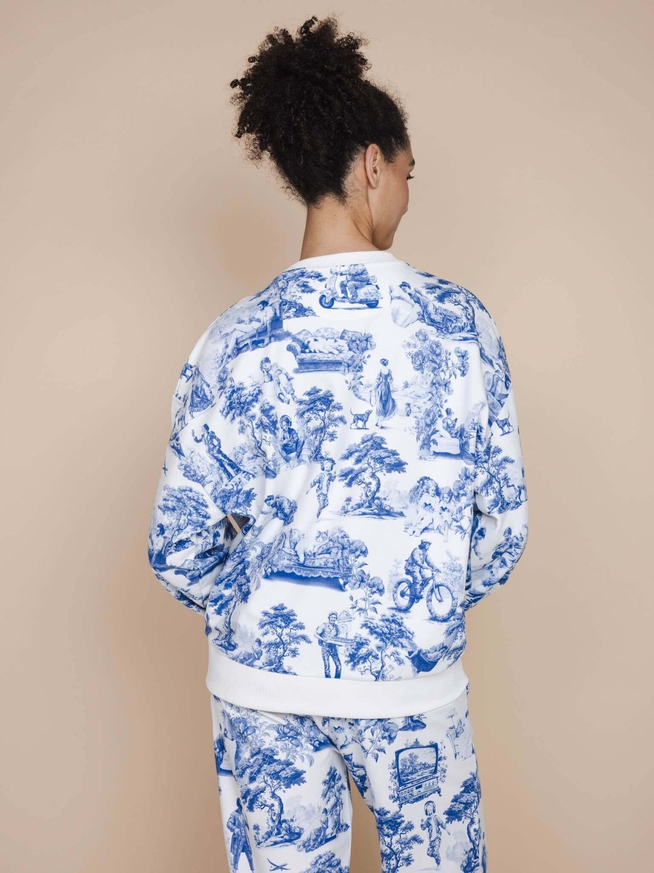 Vrouw in SNURK Toile De Modern Joy Sweater Unisex met klassiek motief aan de achterkant.